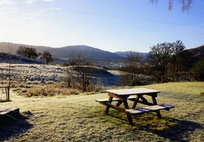 a picnic table sitting on top of a field at Cosy & compact Rowan Lodge no4 in Killin
