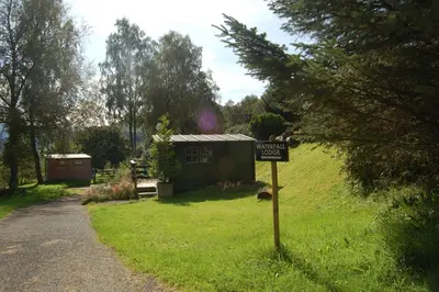 a sign in the grass in front of a tiny house at Cosy & compact Rowan Lodge no2 in Killin