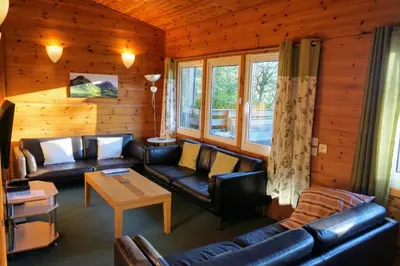 a living room with leather couches and a table at Woodland Gean Lodge in Killin