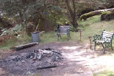 two benches sitting next to a fire in a yard at Woodland Pine Lodge in Killin