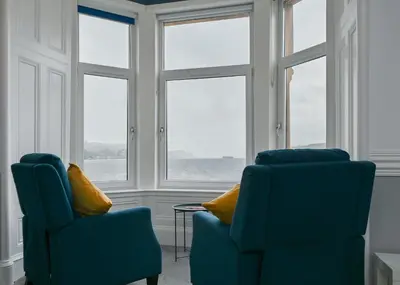 two chairs and a table in a room with windows at MacKays in Oban
