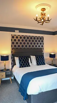 a bedroom with a large bed and a chandelier at MacKays in Oban