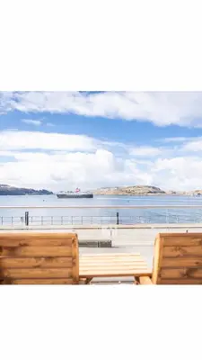 two wooden benches overlooking the water with a ship in the distance at MacKays in Oban