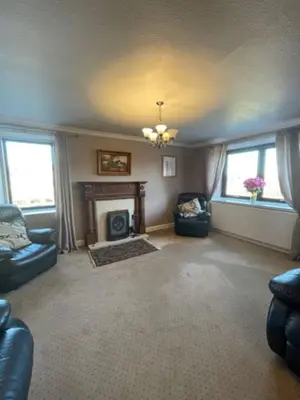 a living room with two chairs and a fireplace at Carminnows Holiday Cottage in Carsphairn
