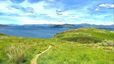 a grassy hill with a view of a body of water at Imperial Apartment in Oban