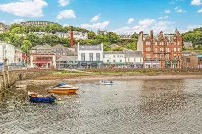 two boats sitting in the water in a city at Imperial Apartment in Oban