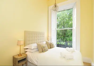 a bedroom with a white bed and a window at Saxe Coburg Place - 325 in Edinburgh