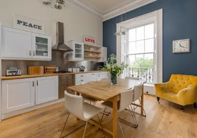 a kitchen with a wooden table and a yellow chair at Saxe Coburg Place - 325 in Edinburgh