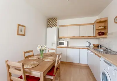 a kitchen with a wooden table with chairs and a sink at Dean Path - 400 in Edinburgh
