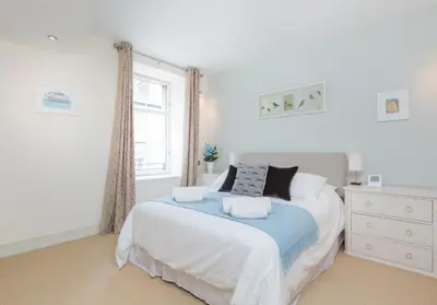 a white bedroom with a bed and a window at Thistle Street - 401 in Edinburgh