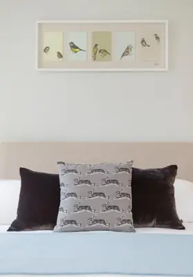 a bed with two pillows and a picture of birds at Thistle Street - 401 in Edinburgh