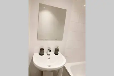 a white bathroom with a sink and a mirror at Cozy Nights - Ibrox Street in Glasgow