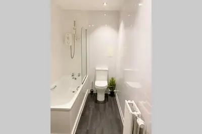 a white bathroom with a tub and a toilet at Cozy Nights - Ibrox Street in Glasgow