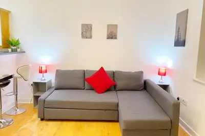 a living room with a gray couch with a red pillow at Cozy Nights - Ibrox Street in Glasgow