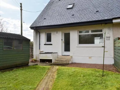 a white house with a green door and a yard at Seaview Cottage in Ellanbeich
