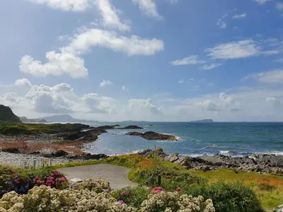 a view of the ocean with rocks and flowers at Seaview Cottage in Ellanbeich