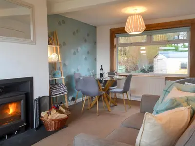 a living room with a table and a fireplace at Seaview Cottage in Ellanbeich