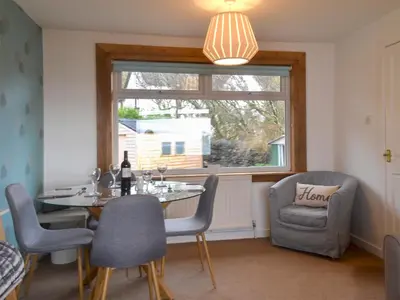 a dining room with a table and chairs and a window at Seaview Cottage in Ellanbeich