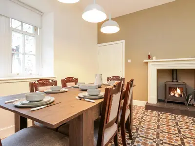 a dining room with a table and a fireplace at East Firwood in Rothesay