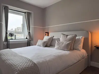 a bedroom with a white bed with a window at Glendevon Hotel in Auchterarder