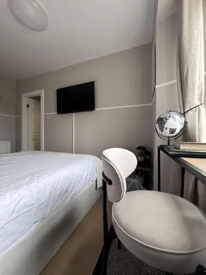 a bedroom with a bed and a chair and a tv at Glendevon Hotel in Auchterarder