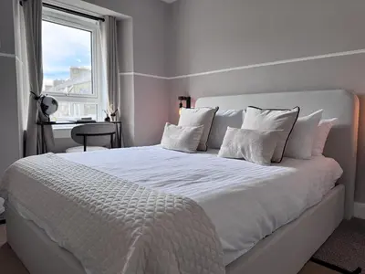 a white bed with white pillows and a window at Glendevon Hotel in Auchterarder