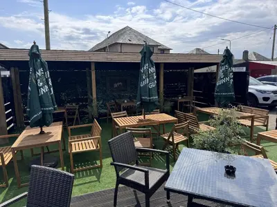 an outdoor patio with tables and chairs and umbrellas at Glendevon Hotel in Auchterarder