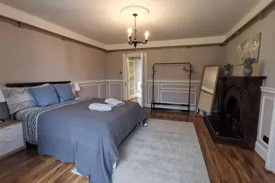 a bedroom with a bed and a chandelier at Broomfield Cottage South Luss in Glasgow