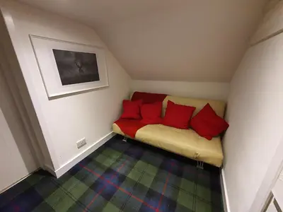 a small room with a couch with red pillows at Cromla Cottage in Corrie