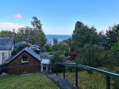 an old brick house with the ocean in the background at Cromla Cottage in Corrie