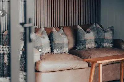 a brown couch with pillows on it with a table at SeaBeds - Luxury Lookouts with Hot Tubs in Glencoe
