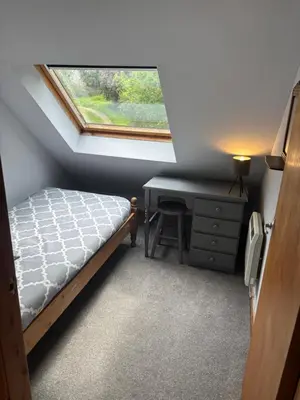 a bedroom with a bed and a desk and a window at Barfad Self Catering Holiday Cottages in Tarbert