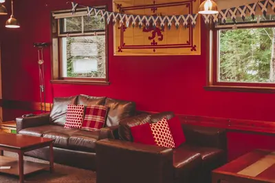 a living room with a leather couch and red walls at Crianlarich Youth Hostel in Crianlarich