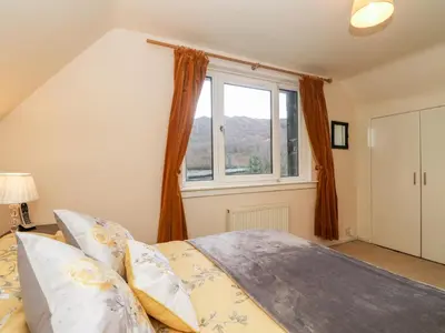 a bedroom with a bed and a window at Glenfinglas Dam Cottage in Callander