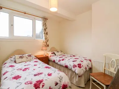 two beds in a room with two windows at Glenfinglas Dam Cottage in Callander