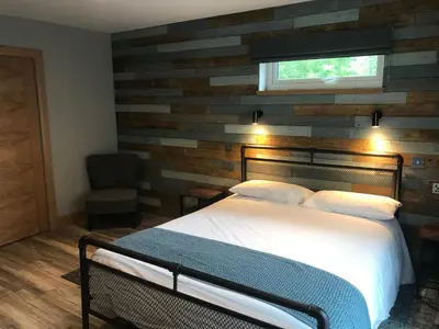 a bedroom with a bed with a wooden accent wall at The Shack & Pods at Inchree in Corran