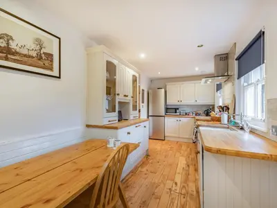 a kitchen with white cabinets and a wooden table at Barjols Cottage - Uk30096 in Wiston