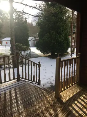 a wooden porch with snow on the ground at Chalet in Tyndrum