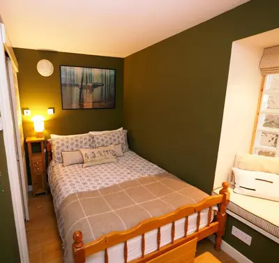 a bedroom with a bed and a green wall at Arrochar Alps Apartment in Arrochar