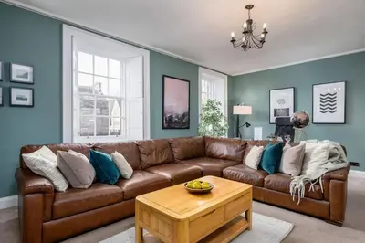 a living room with a brown leather couch and a table at The Stirling Townhouse in Stirling