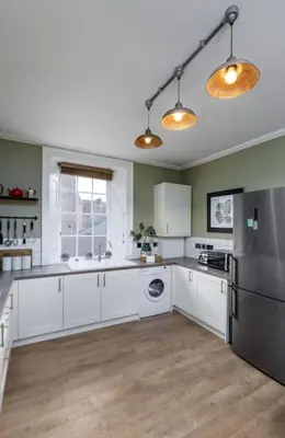 a kitchen with white cabinets and a stainless steel refrigerator at The Stirling Townhouse in Stirling