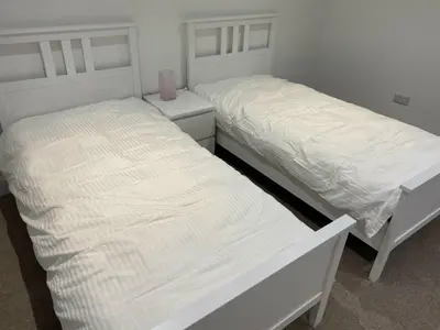 two beds with white sheets in a bedroom at The Smiddy House in Auchterarder