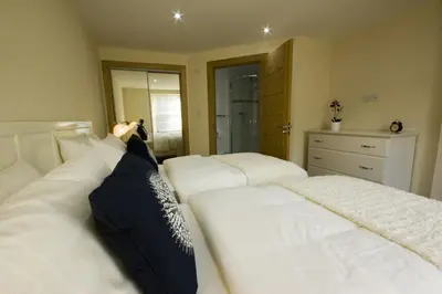 a bedroom with two beds with white sheets at Harviestoun House in Dollar