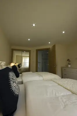 a bedroom with three beds with white sheets at Harviestoun House in Dollar