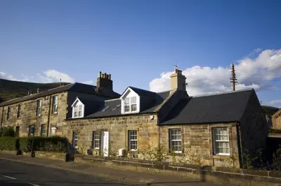 an old stone house on the side of a street at Harviestoun House in Dollar