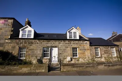 an old brick house with a black roof at Harviestoun House in Dollar