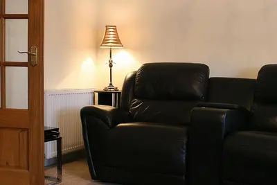 a living room with a leather couch and a lamp at Linden Apartment in Stirling