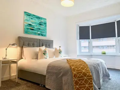 a bedroom with a bed with pillows and a window at Hillington Central in Glasgow