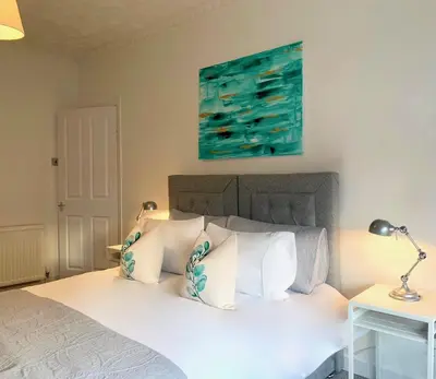 a bed with white pillows and a painting on the wall at Hillington Central in Glasgow