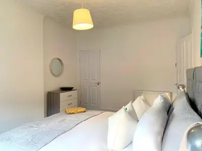 a bedroom with a white bed with white pillows at Hillington Central in Glasgow